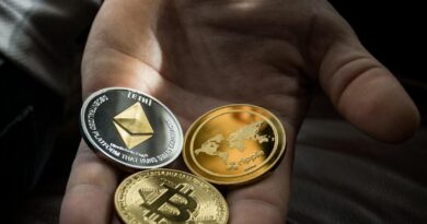 Hand holding Bitcoin, Ethereum, and Ripple coins representing digital currency.