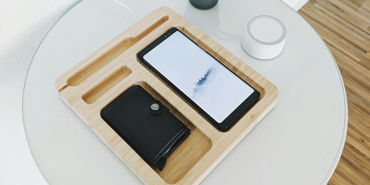 black smartphone with wallet on wooden tray on table