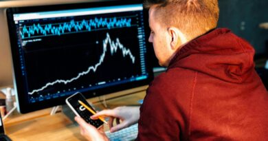 man holding black smartphone with flat screen monitor in front