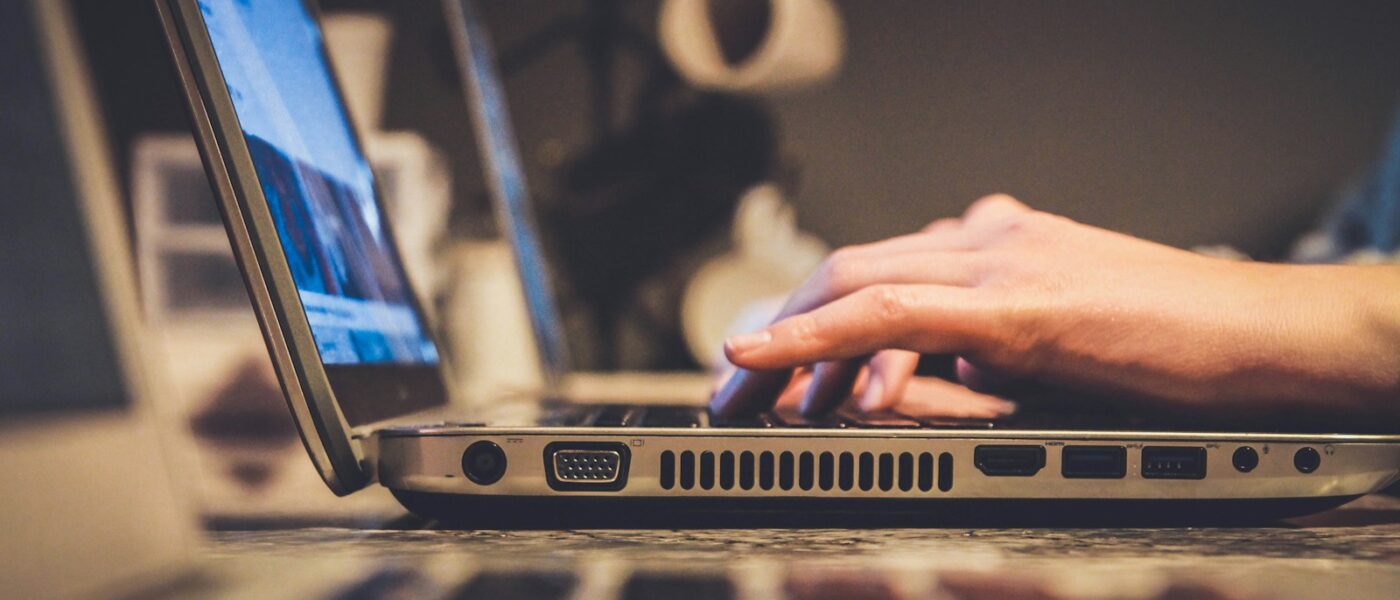 person using silver laptop computer on desk