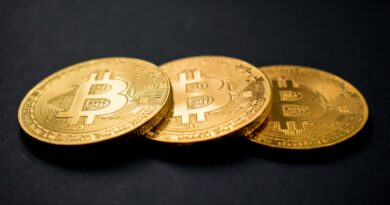 three gold-colored bitcoins on black surface