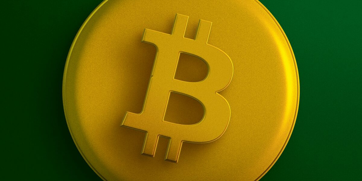 a yellow bit coin sitting on top of a green surface