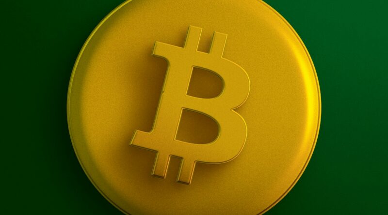 a yellow bit coin sitting on top of a green surface