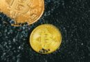 two gold bitcoins sitting on a black surface