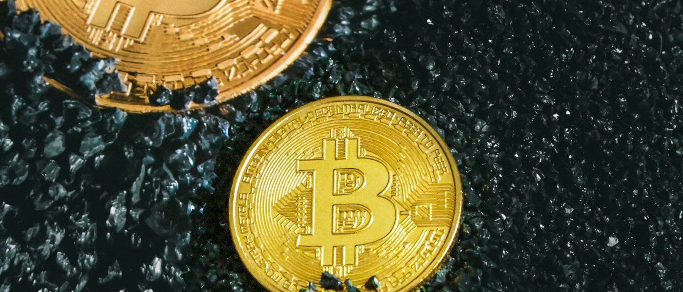 two gold bitcoins sitting on a black surface