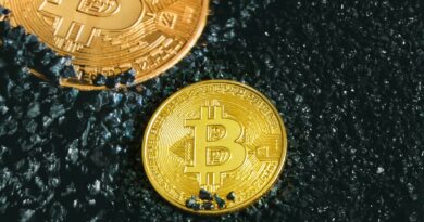 two gold bitcoins sitting on a black surface